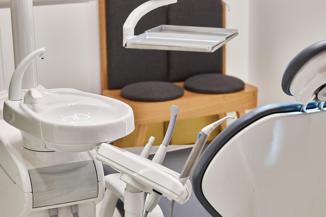 A bright, calm treatment room with a dental chair and wooden shelves